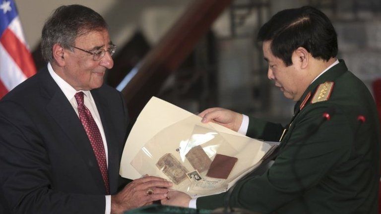 US Secretary of Defence Leon Panetta (L) hands his Vietnamese counterpart artefacts from the war