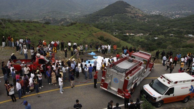 Bodies, covered by white sheets, lie on the road next to the site of a passenger bus crash in the southwestern state of Guerrero