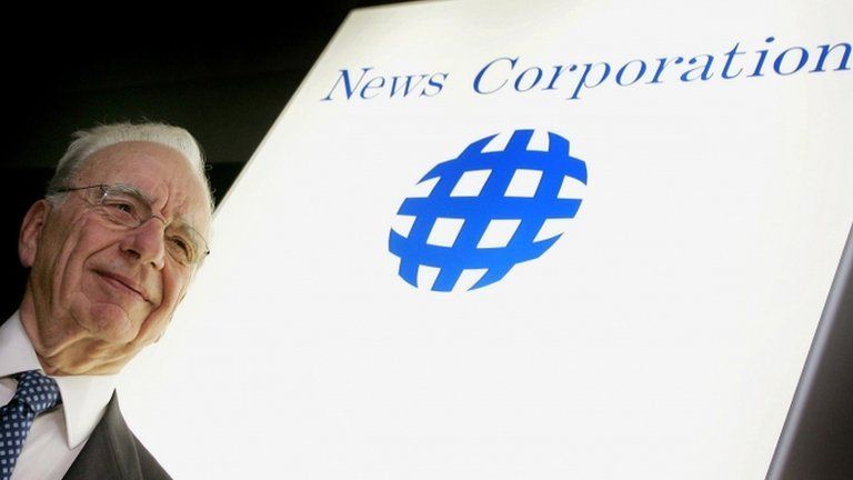 Rupert Murdoch in front of News Corp logo
