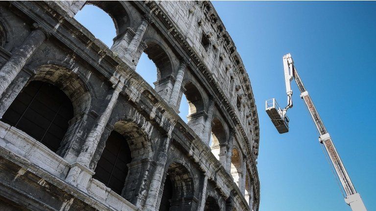 A worker rides on a boom lift as he inspects the Colosseum, 31 July