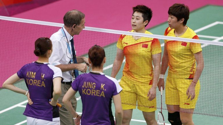 Tournament referee Torsten Berg (2nd L) speaks to players from China (in yellow) and South Korea during their women's doubles group play stage in London on 31 July 2012