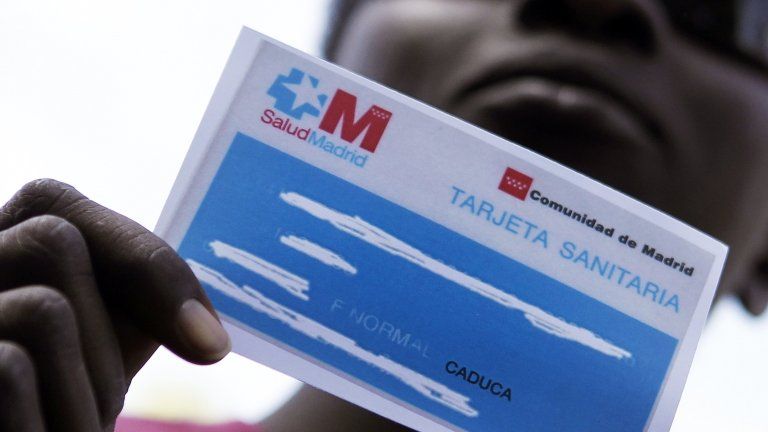 An immigrant protesting against healthcare cuts shows his invalid healthcare card in Madrid, 1 September