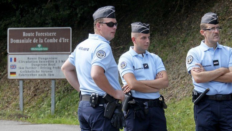 French police guard a road leading to the murder site