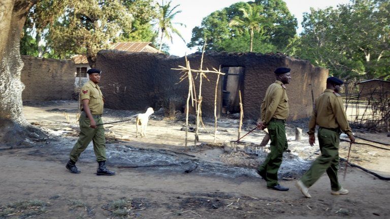 Police walk past the remains of houses which were burned down during clashes in Chamwanamuma village, Tana River delta, north of Mombasa in Kenya Friday, Sept. 7, 2012.