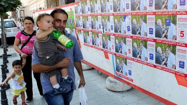 People walk past election posters in Tbilisi, 28 September