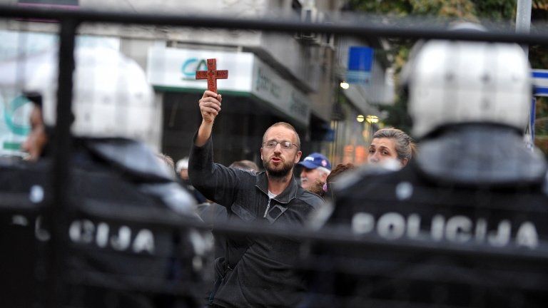 A Christian protester waves a cross outside a Belgrade gallery showing the gay-themed exhibition Ecce Homo, 3 October