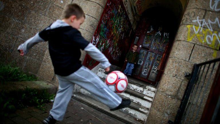 Boys playing football in a derelict building