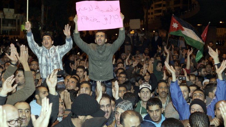 Jordanian protesters hold up banners and their national flag during a demonstration in Amman following an announcement that Jordan would raise fuel prices