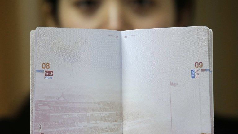 A woman holding up the new Chinese passport with a controversial map