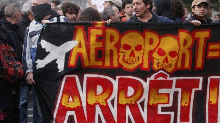 Demonstrators hold a banner saying "Airport, Stop" at a demonstration on Saturday
