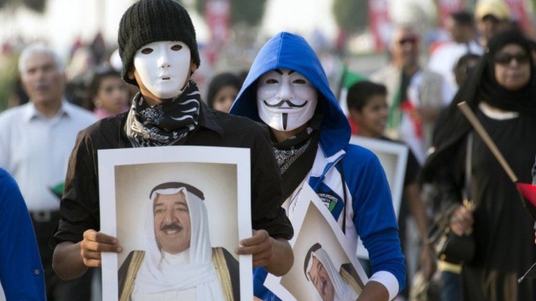 Youths wearing masks carry pictures of Kuwait's Emir during a celebration of the 50th anniversary of the constitution in Kuwait City (10 November 2012)