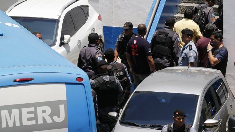 Arrested police officers arrive at their headquarters in Rio de Janeiro