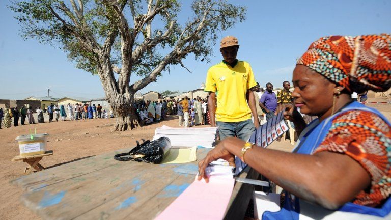 An electoral officer gives ballot papers to a voter upon his arrival at Bole polling station in Ghana's northern region on December 7, 2012.