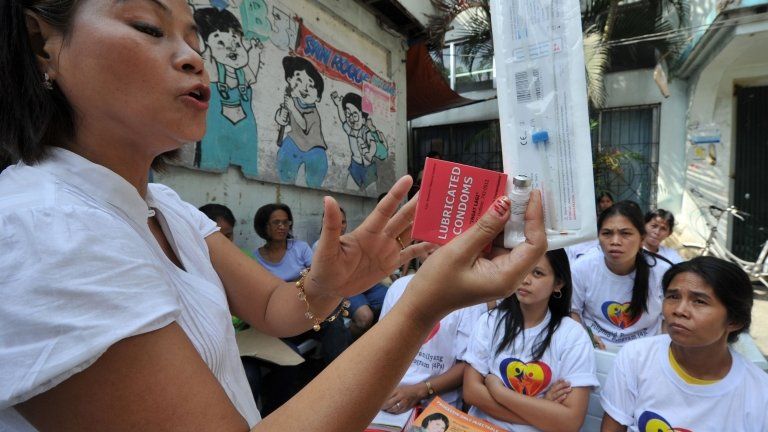 Archive photo of a Filipino health worker holding samples of contraceptives, March 2011
