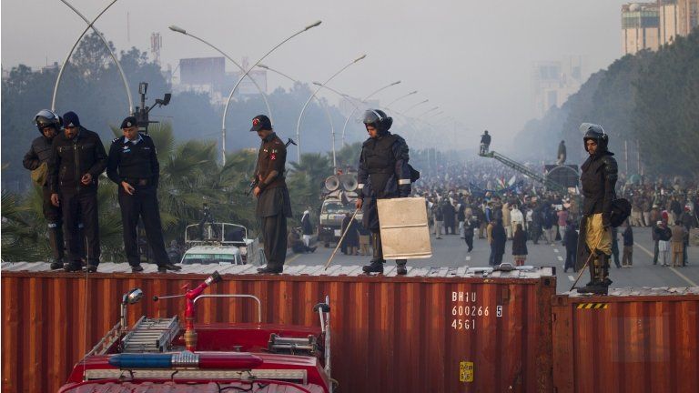 Pakistani police officers stand guard atop shipping containers while supporters of Pakistan Sunni Muslim cleric Tahir-ul-Qadri atage an anti government rally in Islamabad, Pakistan on Tuesday, Jan. 15, 2013.