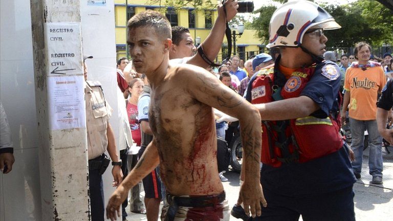 A rescue worker walks with an unidentified injured man during an uprising at the Centro Occidental prison in Barquisimeto, Venezuela