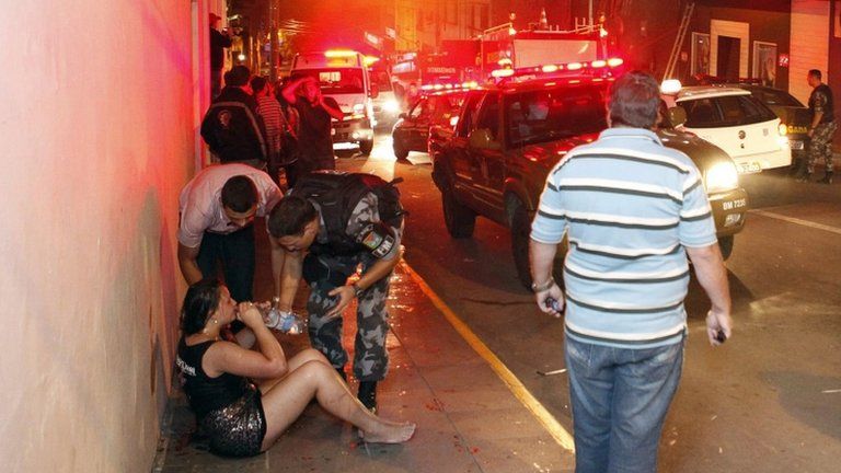A survivor is helped by emergency workers near the Kiss club in Santa Maria, Brazil, 27 January