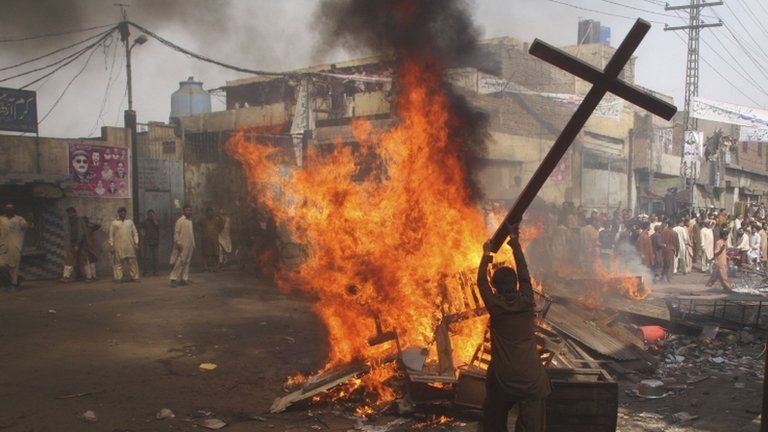 A rioter burns a cross in Lahore, 9 March