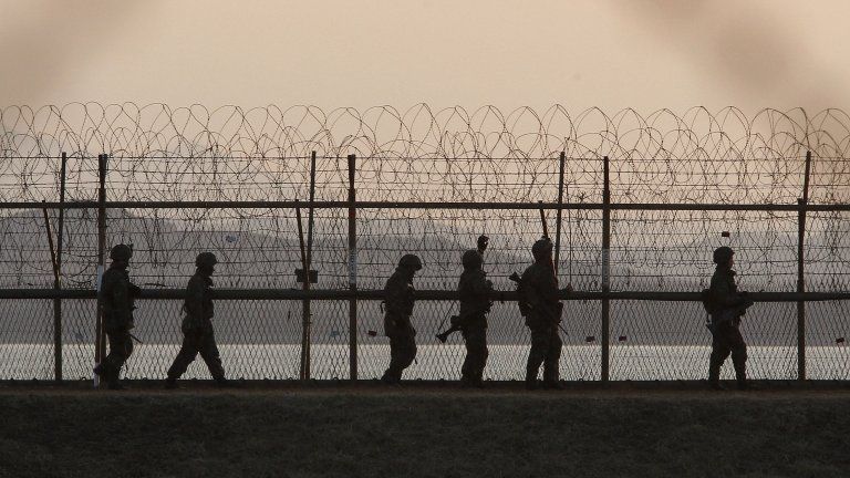 South Korean army soldiers patrol along a barbed-wire fence near the border village of Panmunjom in Paju, South Korea, Tuesday, March 26, 2013