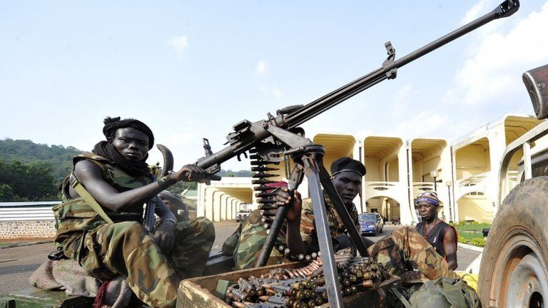 Seleka rebels sitting on a pick up truck mounted with a machine gun stand attention outside the pillaged presidential palace of deposed president in Bangui on 28 March 2013