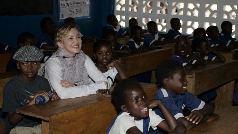 US pop star Madonna (2nd L) sits on April 2, 2013 with the two children she adopted in Malawi, David Banda (L) and Mercy James (3rd R), in a classroom at the Nkoko Primary School