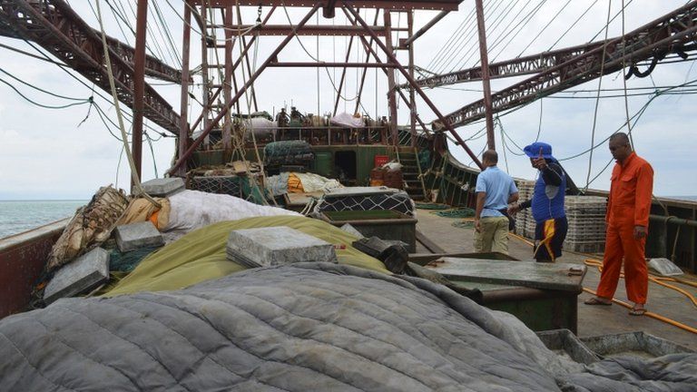 Members of the Philippine Coast Guard inspect the Chinese fishing vessel that ran aground on Monday in the Tubbataha Reef in Palawan province, 9 April 2013