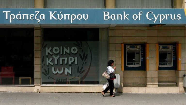 A woman passes outside a branch of Bank of Cyprus in the main shopping street in central capital Nicosia, Cyprus