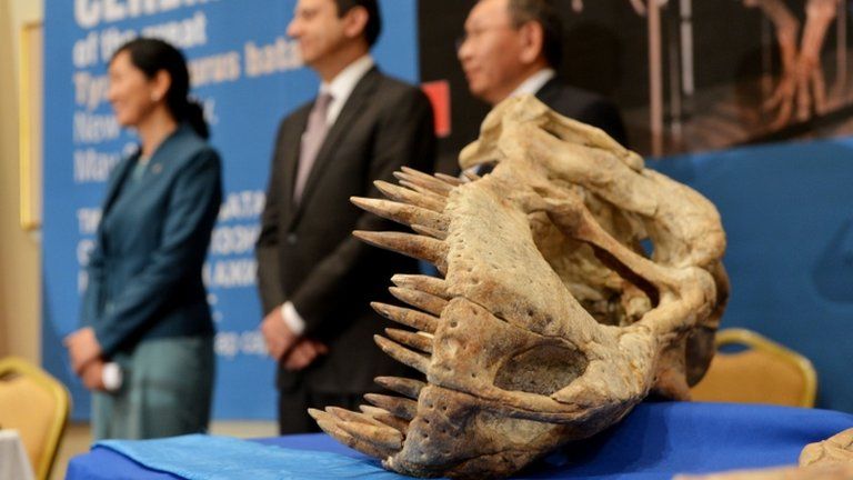 Officials stand next to part of a 70- million-year-old, nearly complete Tyrannosaurus Bataar skeleton that will be repatriated to the government of Mongolia on 6 May 2013 in New York