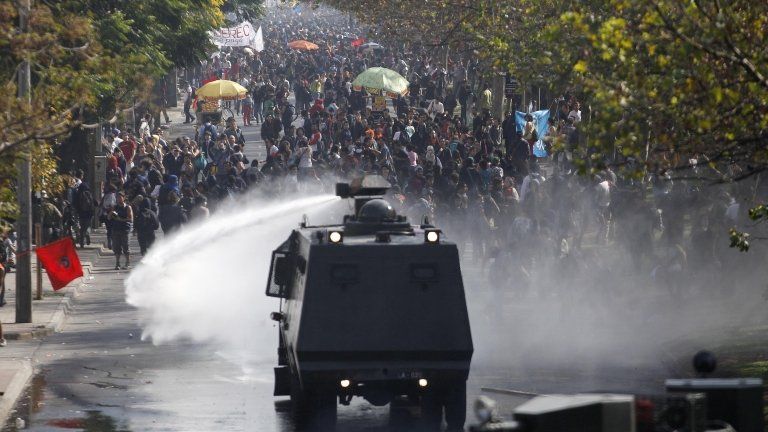 A police water cannon releases a jet of water on student protesters in Chile, April 2013