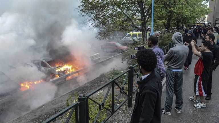 Bystanders watch burning cars in the Stockholm suburb of Rinkeby. 23 May 2013