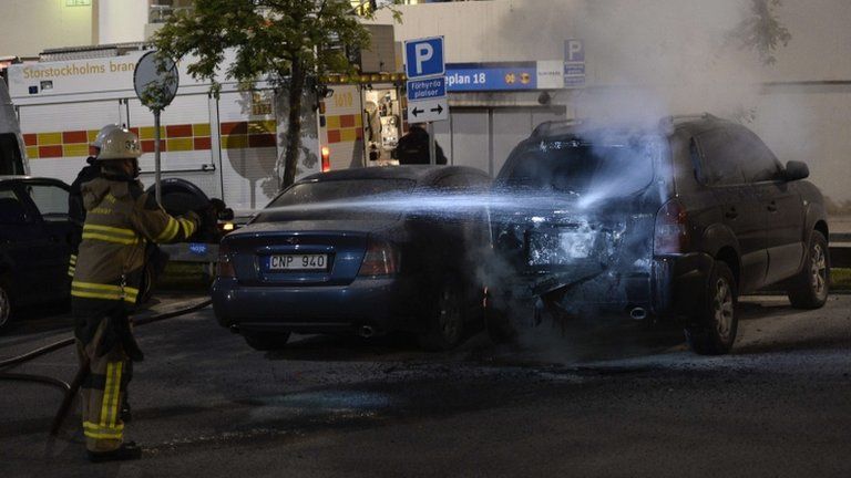 Swedish fireman puts out fire in a car in the Stockholm suburb of Tensta (25 May 2013)