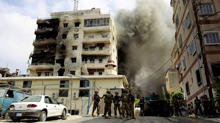 Lebanese soldiers stand by as black smoke rises from a mosque in Sidon where Sunni cleric Sheik Ahmad al-Assir preaches