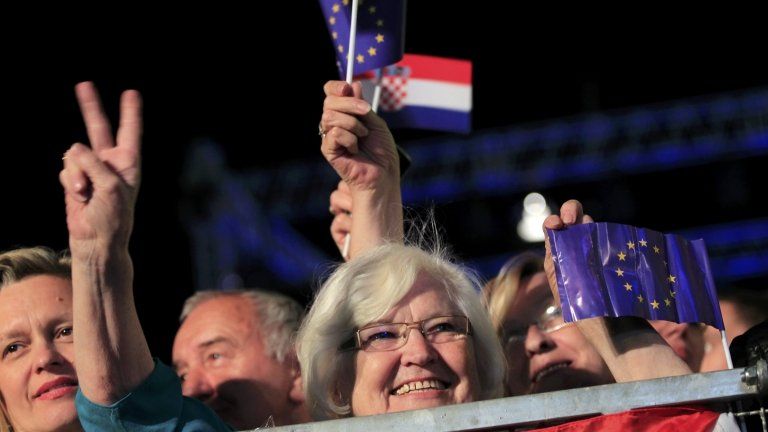 A woman makes victory sign as she holds the EU flag during the celebration of the accession of Croatia to the EU in Zagreb, 30 June 2013.
