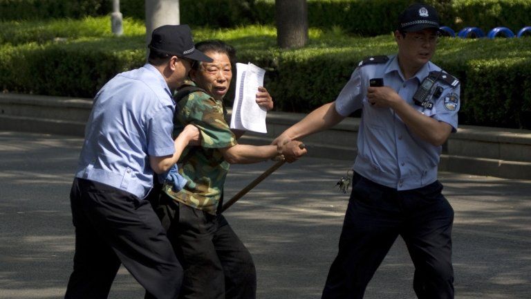 File photo: a petitioner trying to attract public attention is taken away by policemen in Beijing, China, 8 May 2012