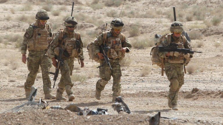 Four British soldiers in desert terrain