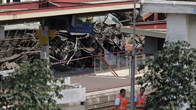 Railways workers are seen at the site where a train derailed at a station in Bretigny-sur-Orge