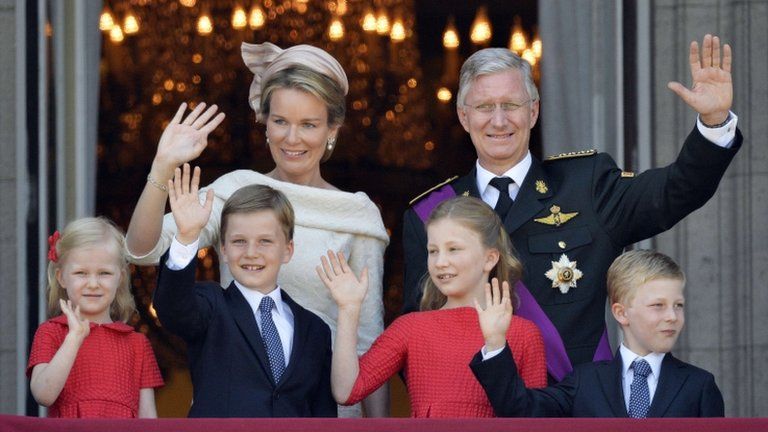 King Philippe, his wife Mathilde and their four children wave to crowds from the balcony of the royal palace in Brussels