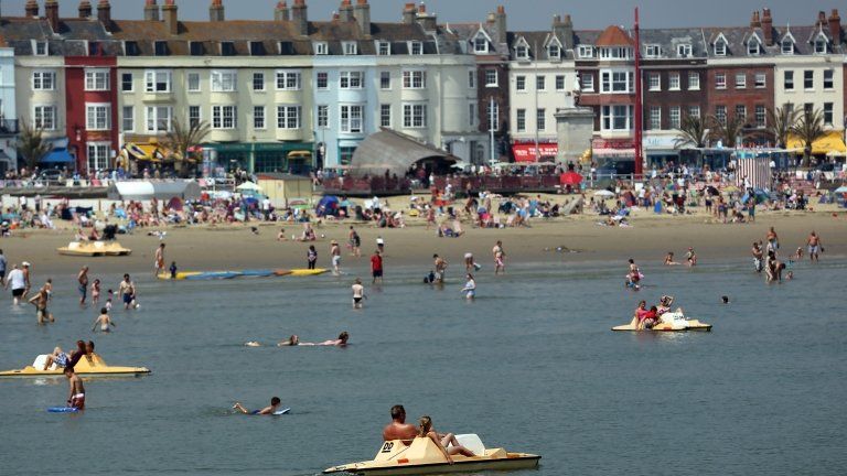 People enjoy the beach on 22 July in Weymouth, England