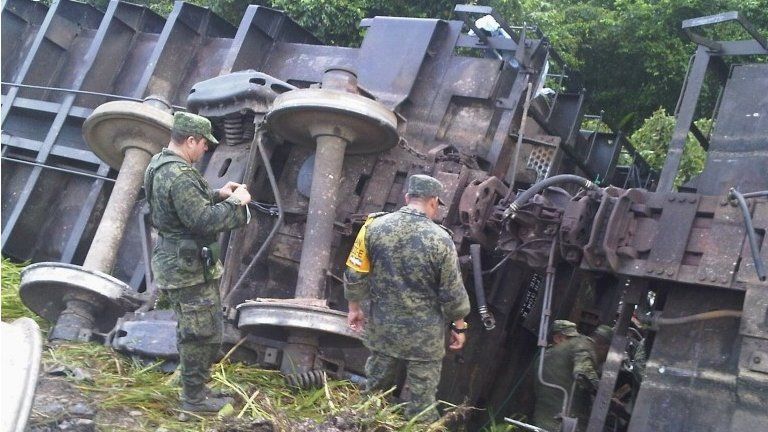 Soldiers inspect an overturned train in southern Mexico 25 August 2013