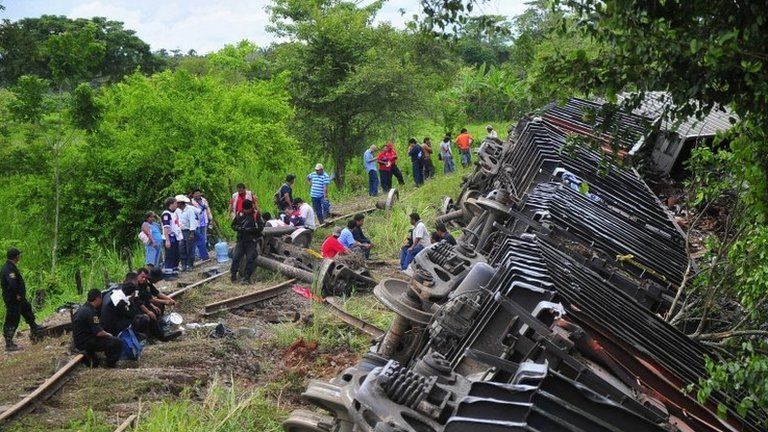 Rescue workers stand next to the overturned carriages of a derailed train in Mexico on 25 August 2013