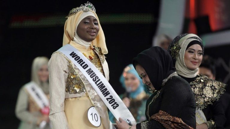Indonesian parliament member Wardatul Asriah, second right, places a sash on Obabiyi Aishah Ajibola of Nigeria after she was named World Muslimah 2013 in Jakarta, Indonesia, Wednesday, 18 September 2013