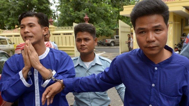 Born Samnang (left) and Sok Sam Oeun (right), are escorted by a prison guard to the supreme court in Phnom Penh on 25 September 2013