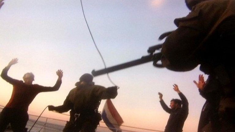 A handout picture taken with camera phone off a computer screen in the Pechora Sea on 19 September 2013, and provided by Greenpeace International shows Russian security forces officers standing on the deck of Greenpeace's Arctic Sunrise.