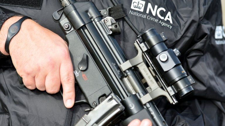 An NCA officer holding a gun