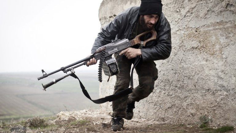 A rebel fighter takes cover during a battle in Azaz (17 December 2012)