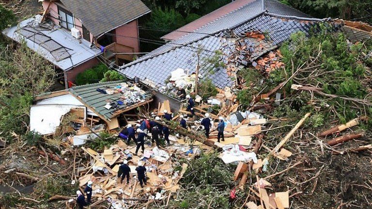 Rescue workers search among collapsed houses following a landslide caused by Typhoon Wipha on Izu Oshima island, south of Tokyo, 16 October 2013