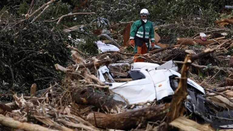 A rescue worker looks for a victim of a landslide caused by Typhoon Wipha in Izu Oshima island, south of Tokyo, 17 October 2013