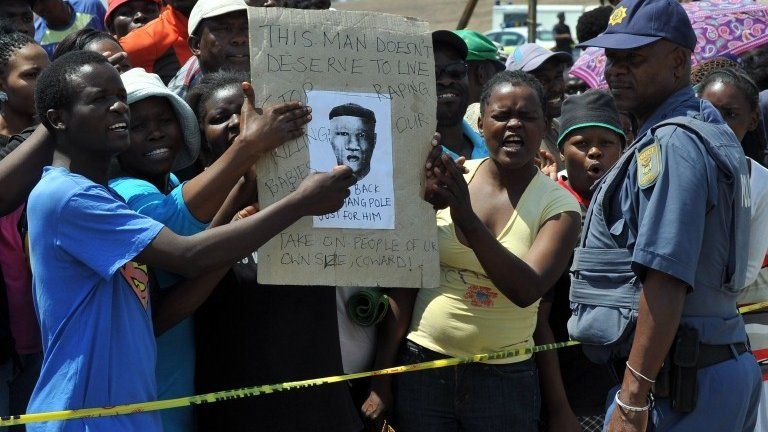 A police officer by protesters demonstrating in Diepsloot, north of Johannesburg, over the rape and murder of two toddlers - Friday 18 October 2013
