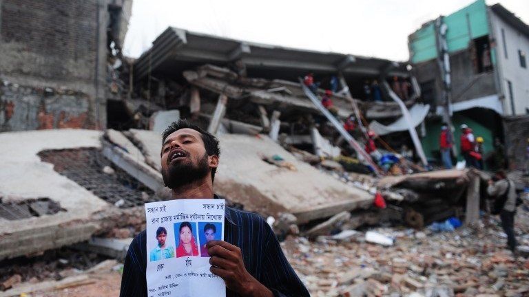 Man holding pictures of missing relatives at the Rana Plaza site, Banagladesh, April 2013