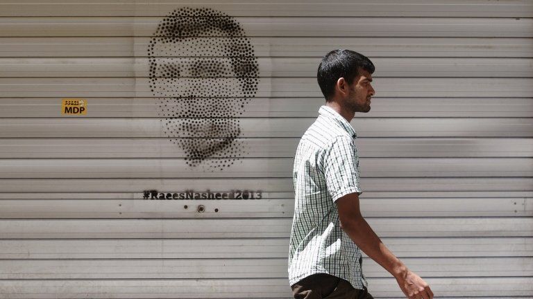 Man walks past image of Mohamed Nasheed